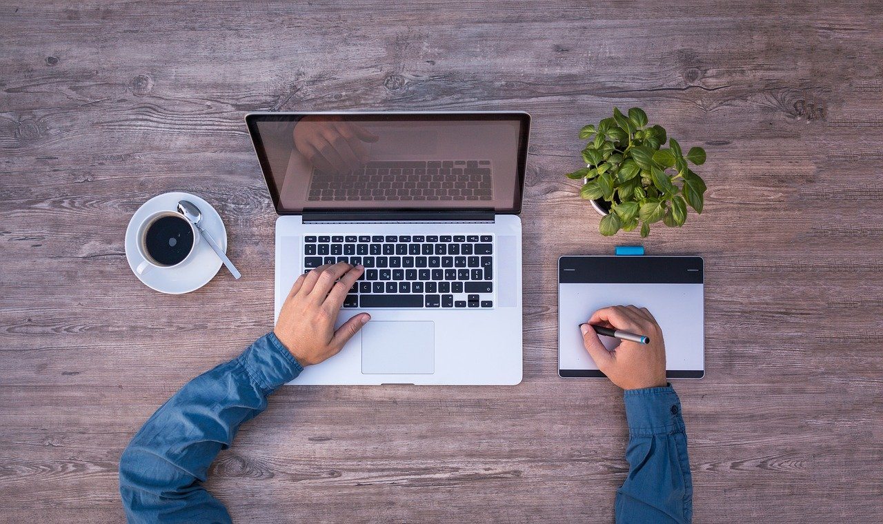 Man working at laptop, pen and paper